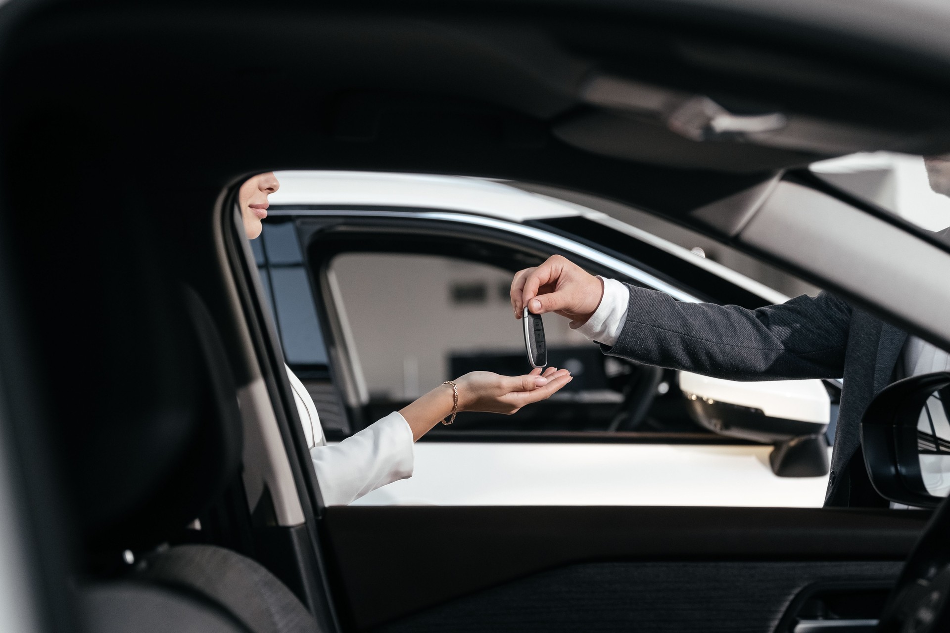A close-up of key handover at a car dealership. This moment highlights the culmination of an expensive purchase, symbolizing a new life with the car and a touch of luxury.
