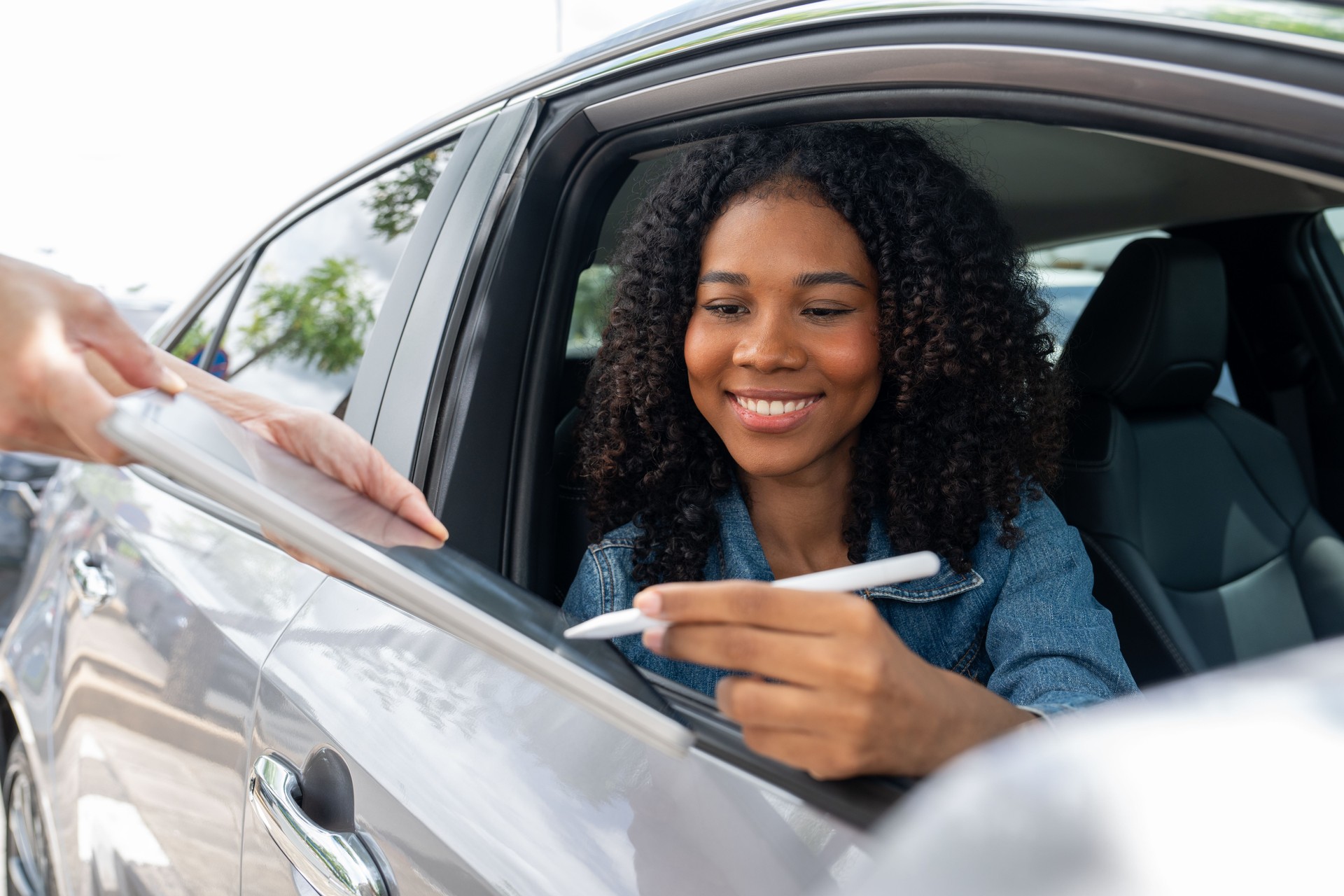 African American women sign contact on digital tablet rental or buying car.